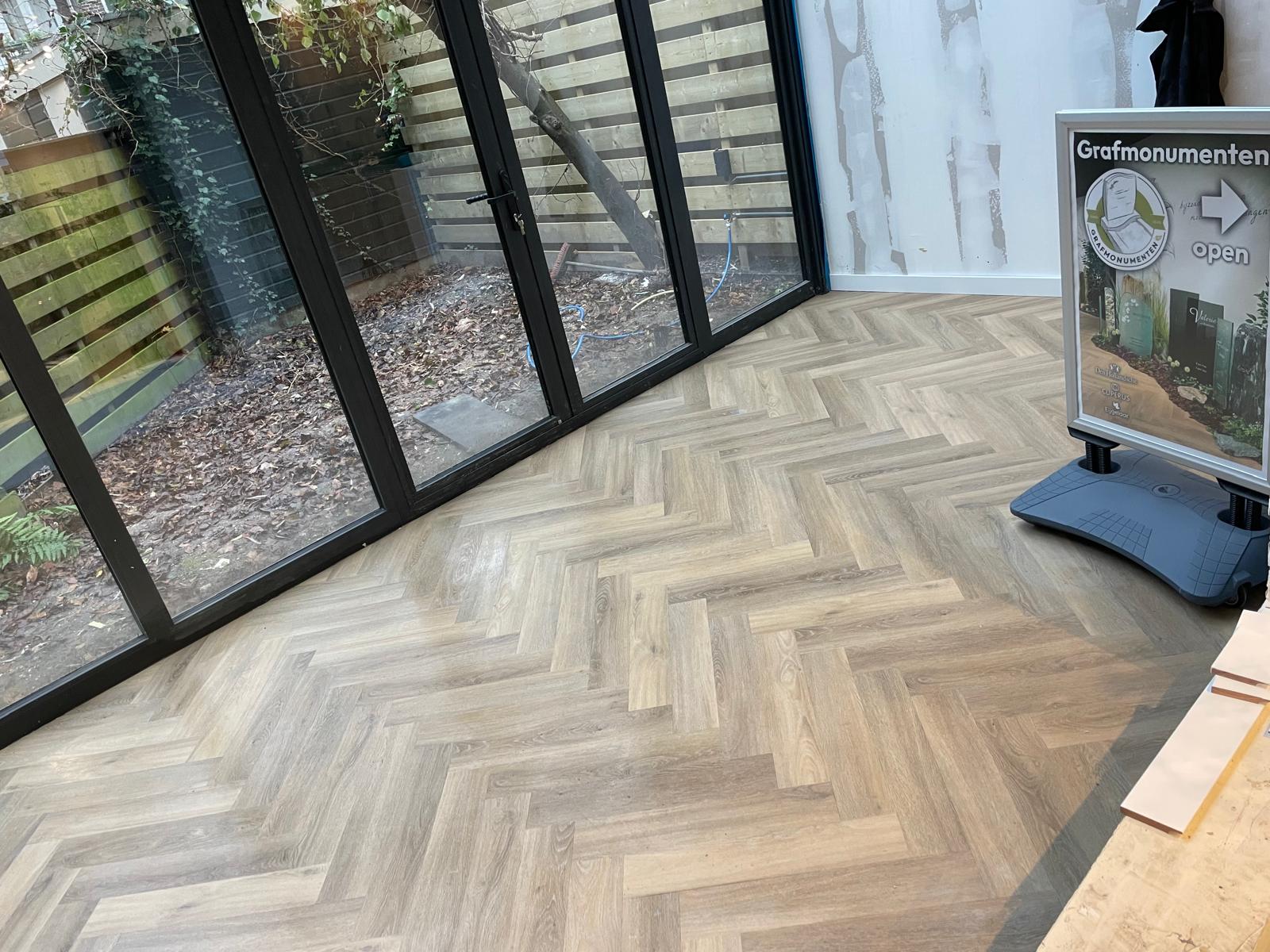 Timmerman Roelofarendsveen legt visgraat PVC-vloer in showroom met tuindoorzicht